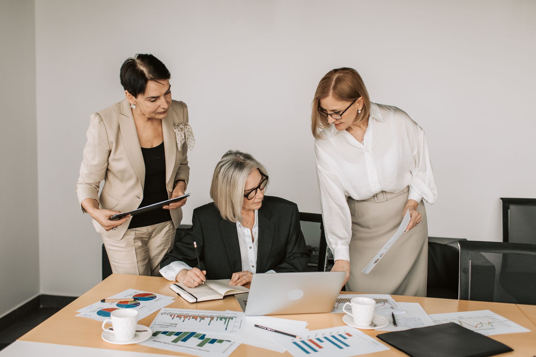 Three businesswomen discussing documents during a meeting in a modern office setting. — 11 Creative Ways to Use a Bottle Open