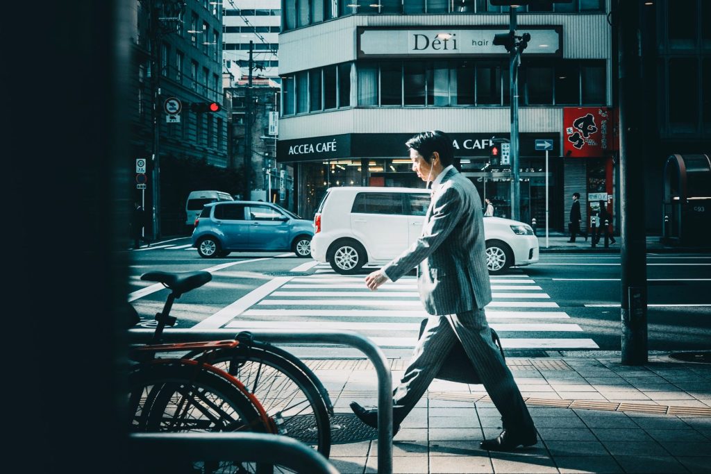 Businessman in suit crossing street in vibrant city setting. — Amex Gift Cards: The Ultimate Gift for Shopping Freedom