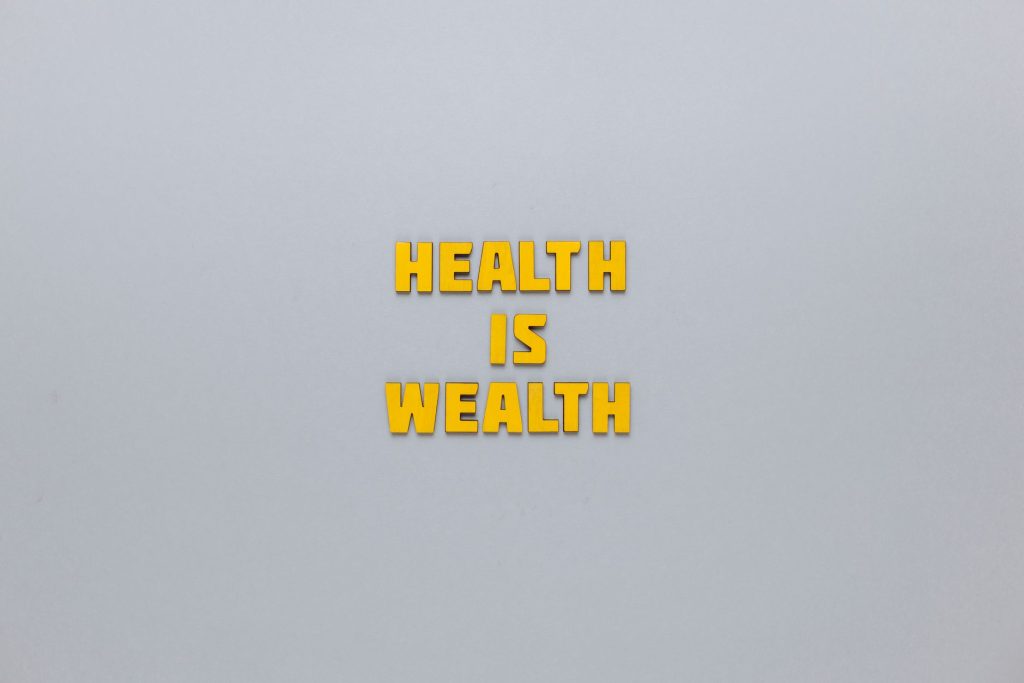 Inspirational phrase 'Health is Wealth' in bold yellow letters on a neutral gray background. — Dr. Scott Kamelle Delivering C