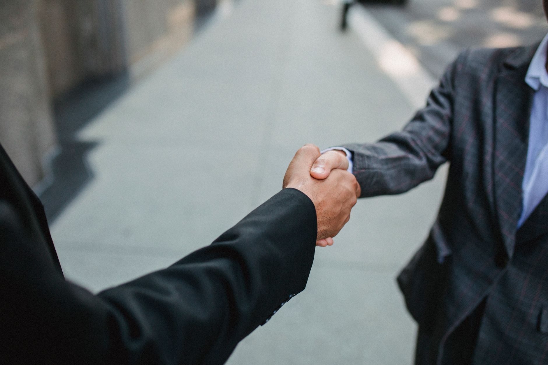 Close-up of two businessmen shaking hands outside, symbolizing partnership and agreement. — Navigating Change: Updates and Im
