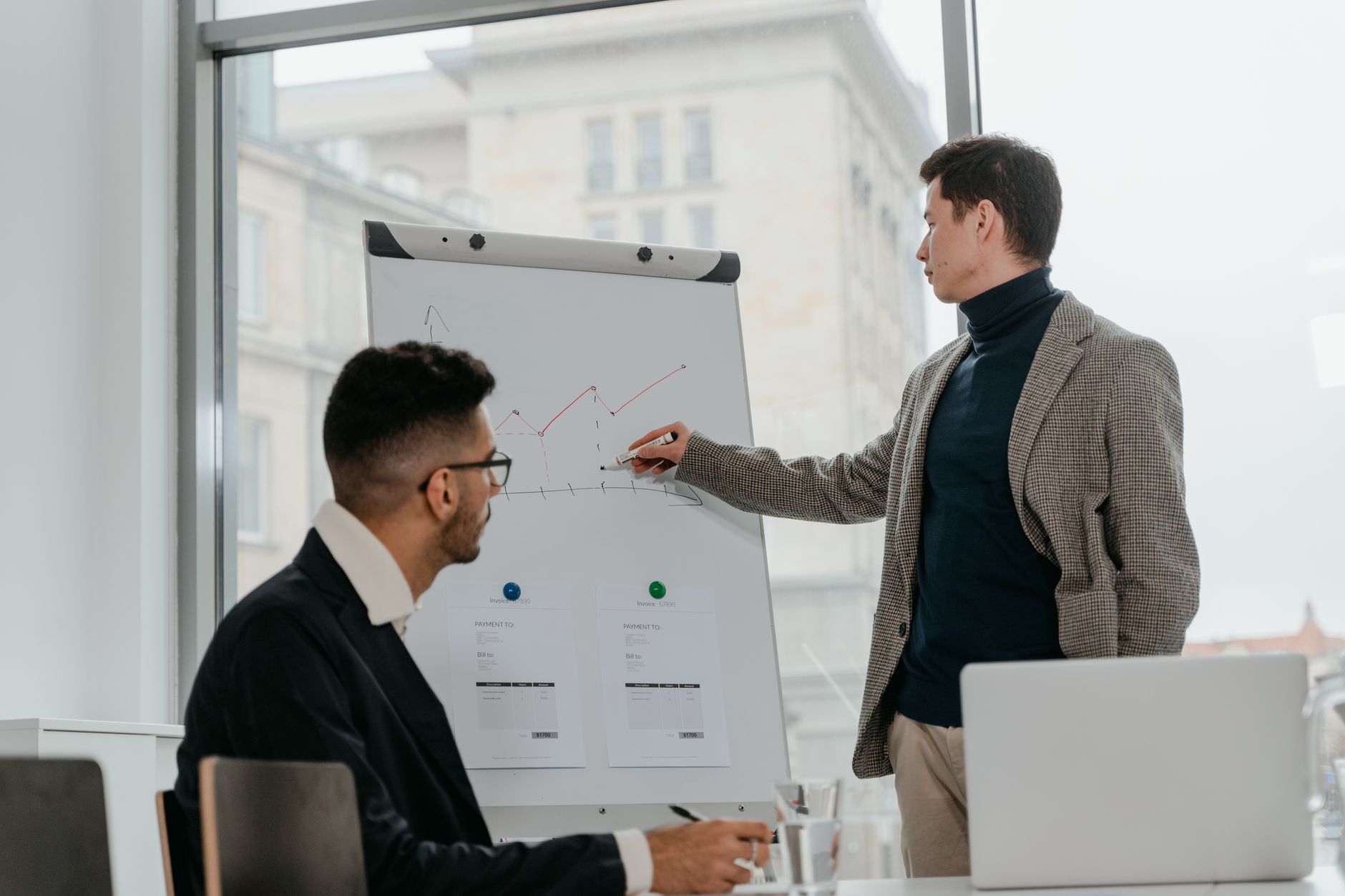 Two businessmen discussing data on a flipchart in a contemporary office setting. — Why Natural Remedies Can Help Neutralize O